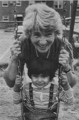 Lola Nash, EBJ's first director smiling with a child on a swing